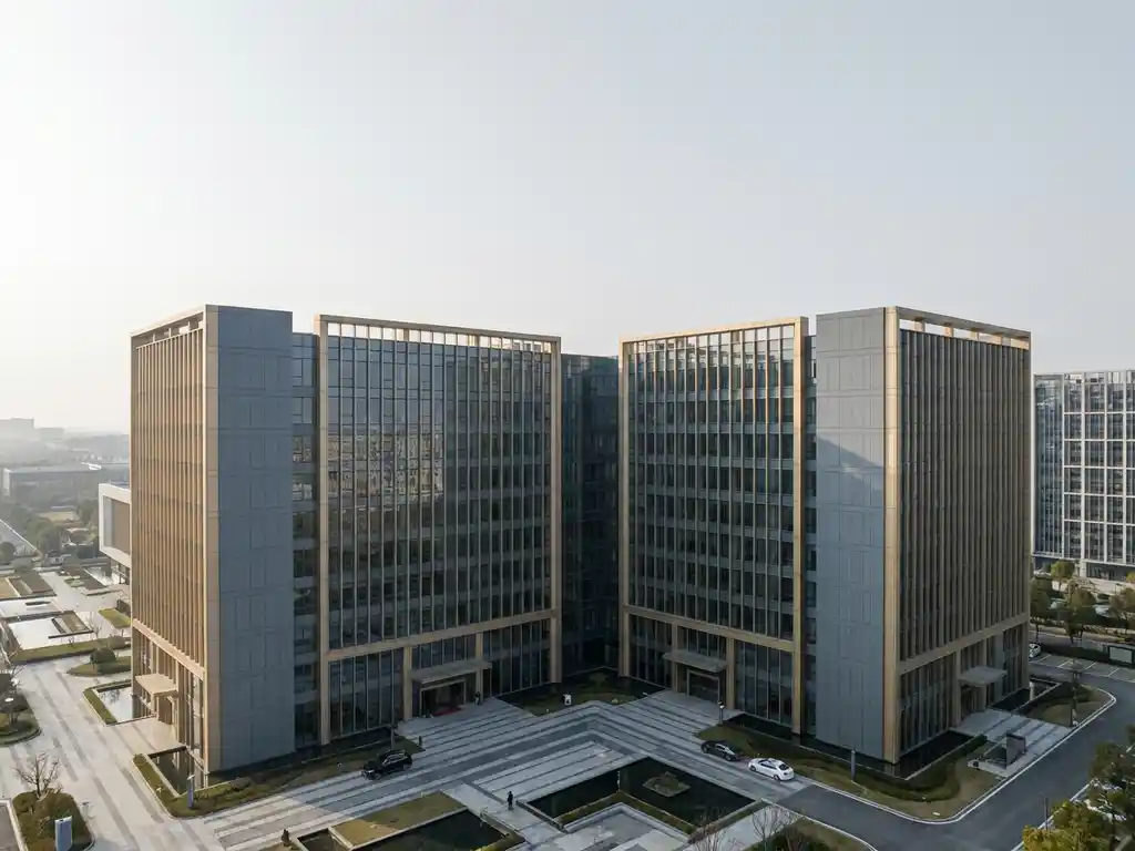 Twee minimalistische kantoorgebouwen in leisteengrijs en champagnegoud die naadloos samensmelten tot één structuur, luchtperspectief.